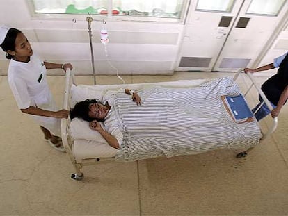 Dos enfermeras del hospital de Sangla conducen una camilla con una herida en los atentados de Bali, en la noche del sábado.