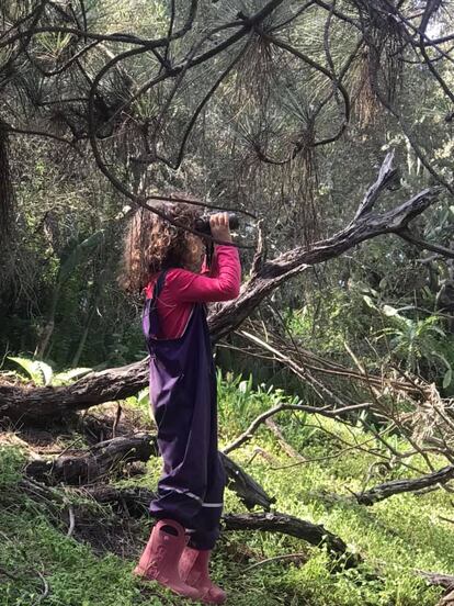 Una alumna de la escuela en la naturaleza Bosqueko observa varias aves desde el bosque con sus prismáticos.