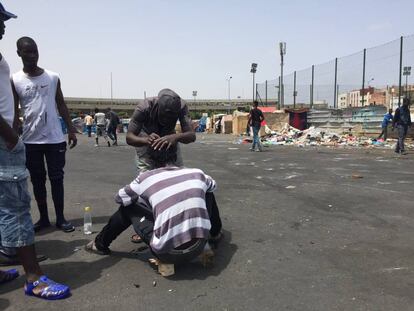 Un migrante corta el cabello a un compañero en el campamento de Casablanca.