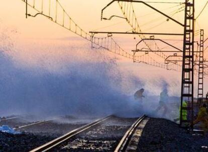 Operarios de Renfe intentaban ayer, entre ola y ola, reparar los deperfectos que causaba el mar en la línea de renfe del Maresme.