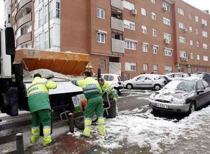 Operarios de limpieza echan sal para combatir la nieve en las calles de Madrid.