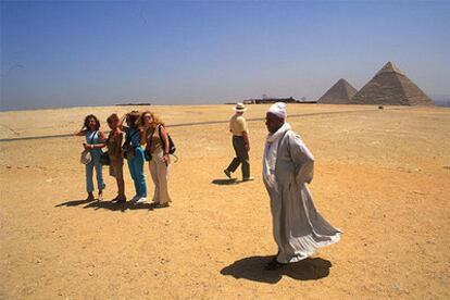 Un grupo de turistas en la meseta de Guiza, en El Cairo, con las pirámides de Kefrén, que aún conserva parte del revestimiento de caliza blanca, y Keops.