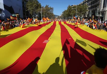 Una bandera catalana es llevada por los manifestantes por el paseo de Gràcia de Barcelona.