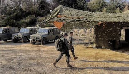 Dos dels soldats passant per davant dels vehicles i la carpa mimetitzada.