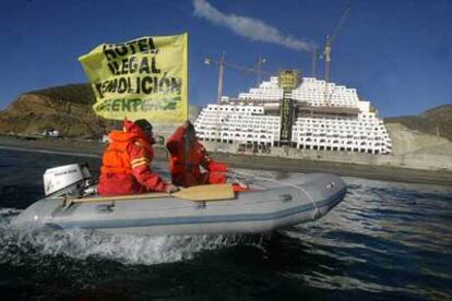 Los activistas de Greenpeace, durante su acción para exigir la demolición del hotel, al fondo.