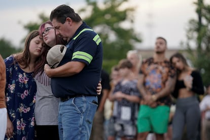 Familias se abrazan, reunidos en un parque cercano a la escuela.