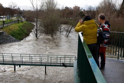 Dos personas observan en caudal del río Manzanares, este viernes en Madrid. 