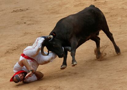 Un corredor es embestido por una vaquilla al final del tercer encierro de San Fermín.