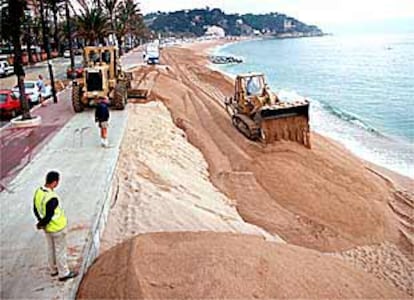 Las excavadoras trasportan la arena de un lado a otro en la playa de Lloret de Mar.