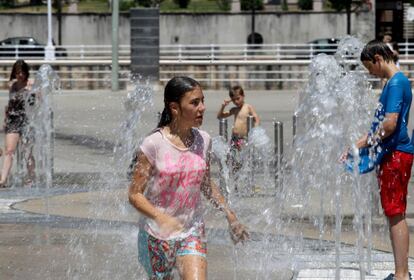 Jovenes se refrescan en una fuente en las inmediaciones del Museo Guggenheim de Bilbao.