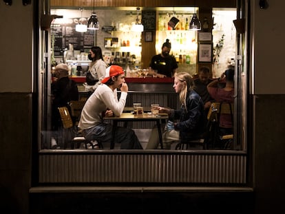 Dos jóvenes en el interior de un bar en el barrio de las Letras, en Madrid.