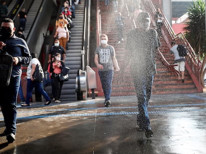 Usuários passam por zona de desinfecção ao sair de uma estação de metrô na cidade de Osasco, em São Paulo.