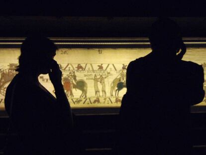 Dos personas miran uno de los tramos del Tapiz de Bayeux.