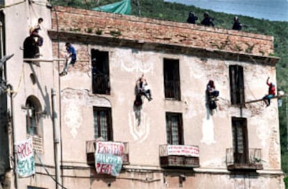 Cuatro de los jóvenes <i>okupas</i> colgados con cuerdas y arneses, ayer, en la fachada de Can Masdeu.
