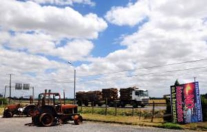 Un camión maderero cruza frente a unos tractores agrícolas quemados tras salir de la protesta que realizó el gremio de camioneros de Chile, este 7 de enero de 2013, en Temuco (Chile).