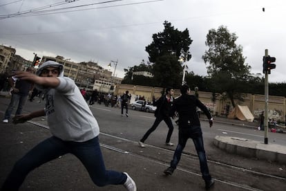 Jóvenes lanzan piedras durante la batalla campal entre seguidores y detractores de Morsi a las puertas del palacio presidencial.