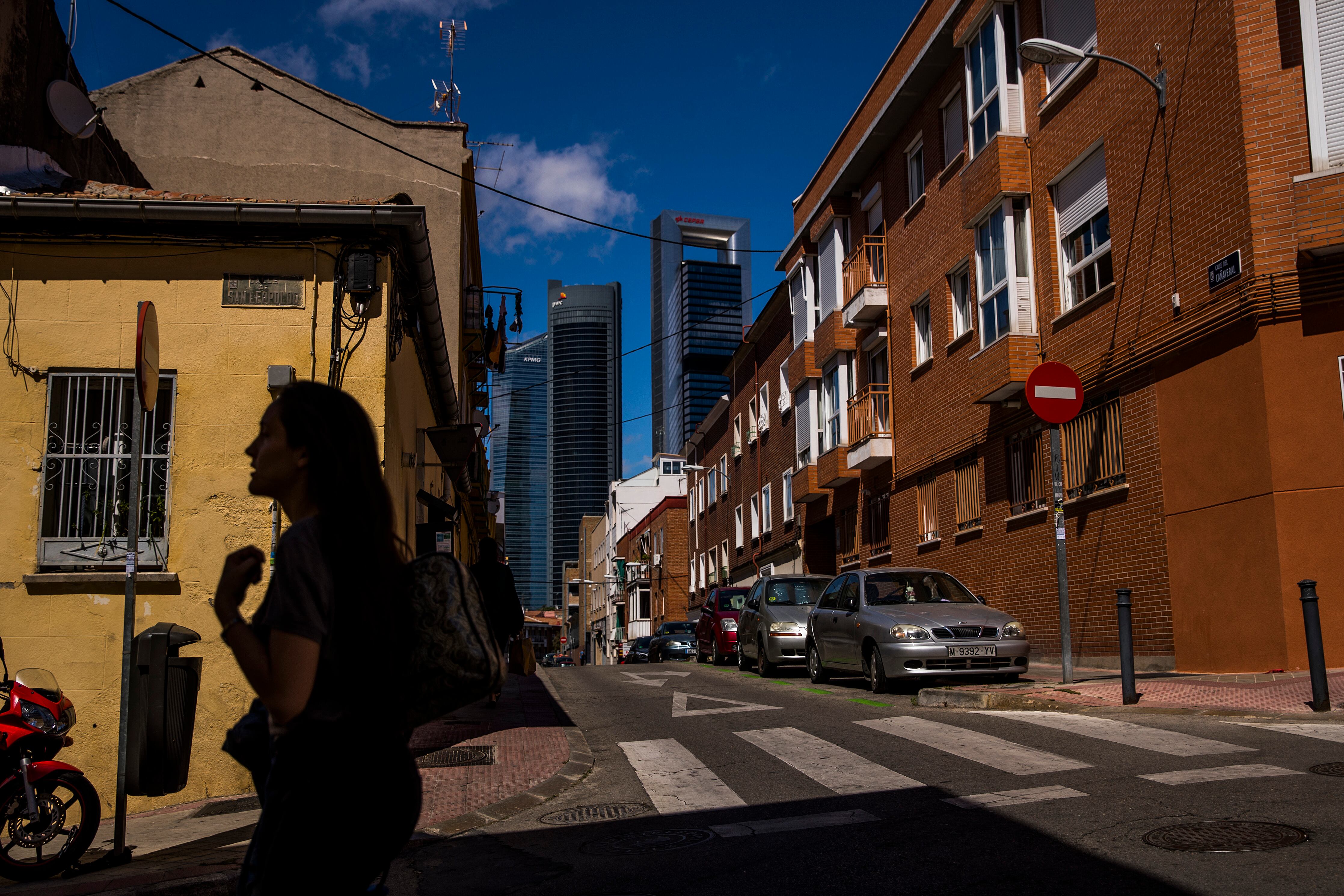 Una mujer camina por la calle Cañaveral de Madrid, con las Cuatro Torres al fondo.