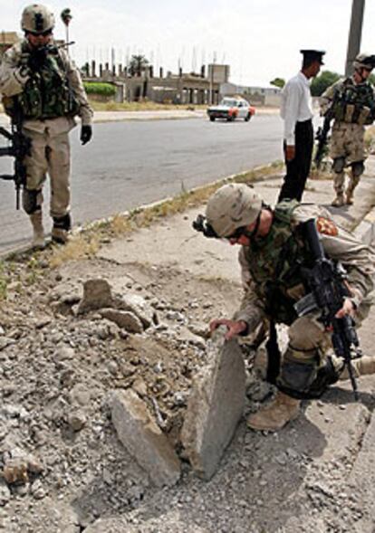 Un soldado examina el lugar de una explosión tras el ataque a un convoy en Mosul.