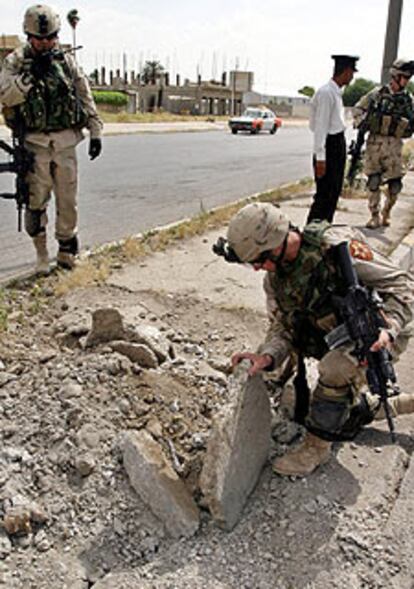 Un soldado examina el lugar de una explosin tras el ataque a un convoy en Mosul.