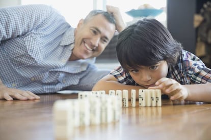 Un padre juega al dominó con su hijo. 