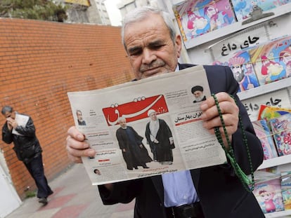 Un hombre sostiene un periódico, este domingo en Teherán, con las imágenes de Rafsanjani y Rohaní.