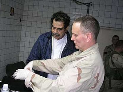 Un agente del FBI escanea las huellas dactilares de Sadam Husein para incluirlas en una base de datos.