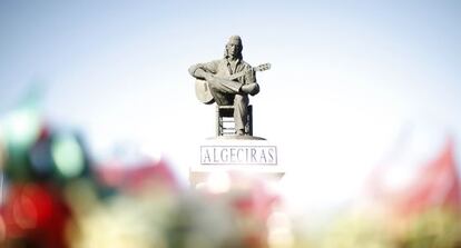 Flores frente a una estatua de Paco de Luc&iacute;a en Algeciras.