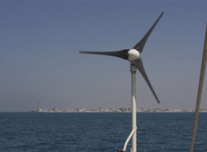 Imagen del pequeño aerogenerador del barco de la organización Oceana, fondeado el pasado miércoles a dos millas de Chipiona. Al fondo, el municipio gaditano.
