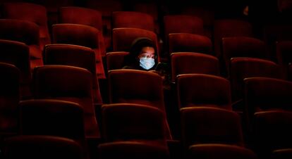 Una persona usa su teléfono móvil en el cine AMC casi vacío, mientras esperan la primera proyección el día de ayer en Burbank, California.