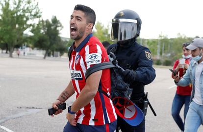 El delantero uruguayo del Atlético de Madrid, Luis Suárez, traspasa el cordón policial para abrazarse con los aficionados en el aparcamiento del estadio José Zorrilla en Valladolid.