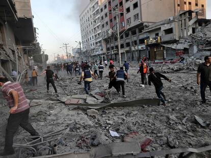 Personal de salvamento y vecinos palestinos corren entre los escombros frente de la Al-Sharouk, que se derrumbó tras un ataque aéreo de Israel, en la ciudad de Gaza.