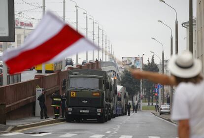 Una mujer ondea la bandera histórica bielorrusa frente a los militares desplegados por el Gobierno, en Minsk.