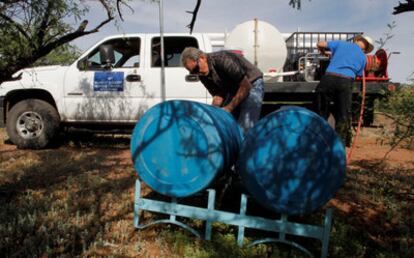 Dos miembros de la organización Humane Borders rellenan los bidones