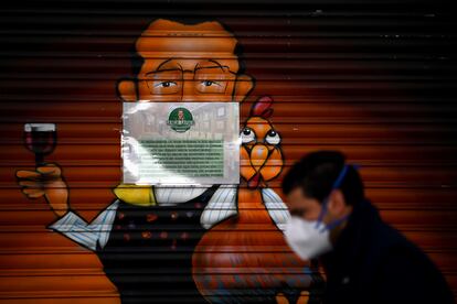 Un hombre con mascarilla camina frente a un restaurante cerrado en Madrid el 2 de abril.