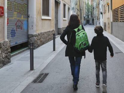 Uma mãe carrega a mochila de seu filho a caminho da escola