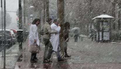 Un grupo de gente anda entre la nieve en la calle Hermanos García Noblejas de Madrid.