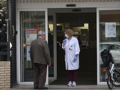 Una sanitaria habla con un paciente a la puerta de un centro de salud en Madrid.