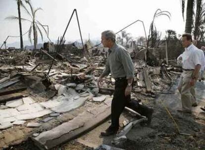 George W. Bush y Arnold Schwarzenegger, gobernador de California, recorren una zona calcinada.