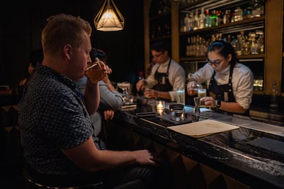 A customer at Handshake Speakeasy drinks a cocktail at the bar.