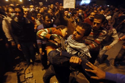 Un manifestante traslada a un joven herido durante los enfrentamientos con las fuerzas antidisturbios en la plaza de Tahrir.