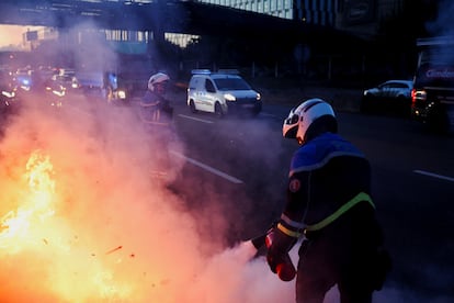 Un agente de policía intentan apagar una hoguera mientras despejan una autopista, durante una protesta del movimiento 'Bloqueemos todo' en Porte d’Aubervilliers, París.