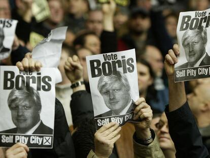 Aficionados del Manchester United muestran carteles de Boris Johnson, en el estadio de Anfield.