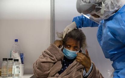 Trinity Ncube, terapeuta ocupacional voluntaria de Nasrec, ayuda a peinarse a la paciente Rebecca Senzani. Para esta mujer, las actividades cotidianas como arreglarse el pelo se han vuelto muy difíciles de realizar desde que contrajo la covid-19.