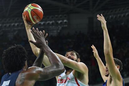 NiKola Mirotic (c) de la selección de España de baloncesto intenta encestar con la presión de los jugadores de Estados Unidos.