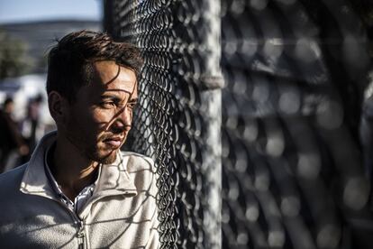 Uma cerca com arame farpado no topo corre ao longo do perímetro da "zona segura" do campo de Moria. Na foto, um jovem olha para dentro do recinto através da cerca.