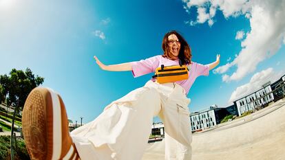 Una chica vestida con ropa de streetwear saltando y sonriendo para la fotografía