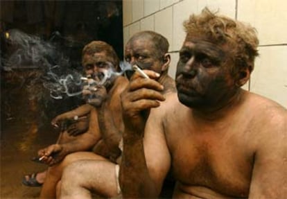 Un grupo de mineros ucranios fuman un cigarrillo mientras esperan su turno para ducharse.