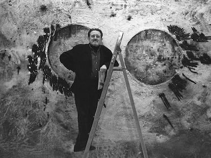 El pintor Juan Genovés, subido a una escalera, delante de una de sus obras en la galería Malborough de Madrid, en 1995. 