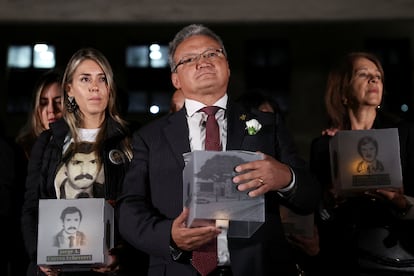 Familiares de las víctimas sostienen una caja de luz durante una ceremonia conmemorativa en el Palacio de Justicia.