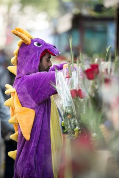 Un venedor disfressat de drac prepara les roses en una parada.